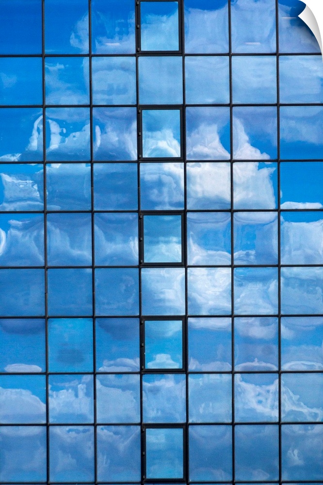 Looking up at a glass building reflecting the sky above.