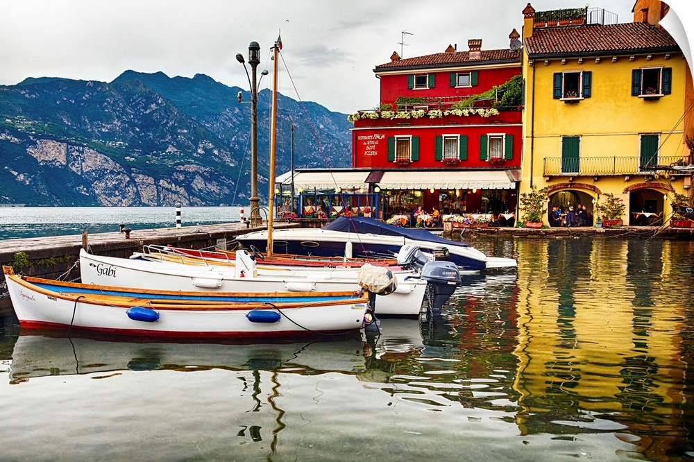 Fine art photo of boats docked in a harbor near brightly painted houses in Italy.