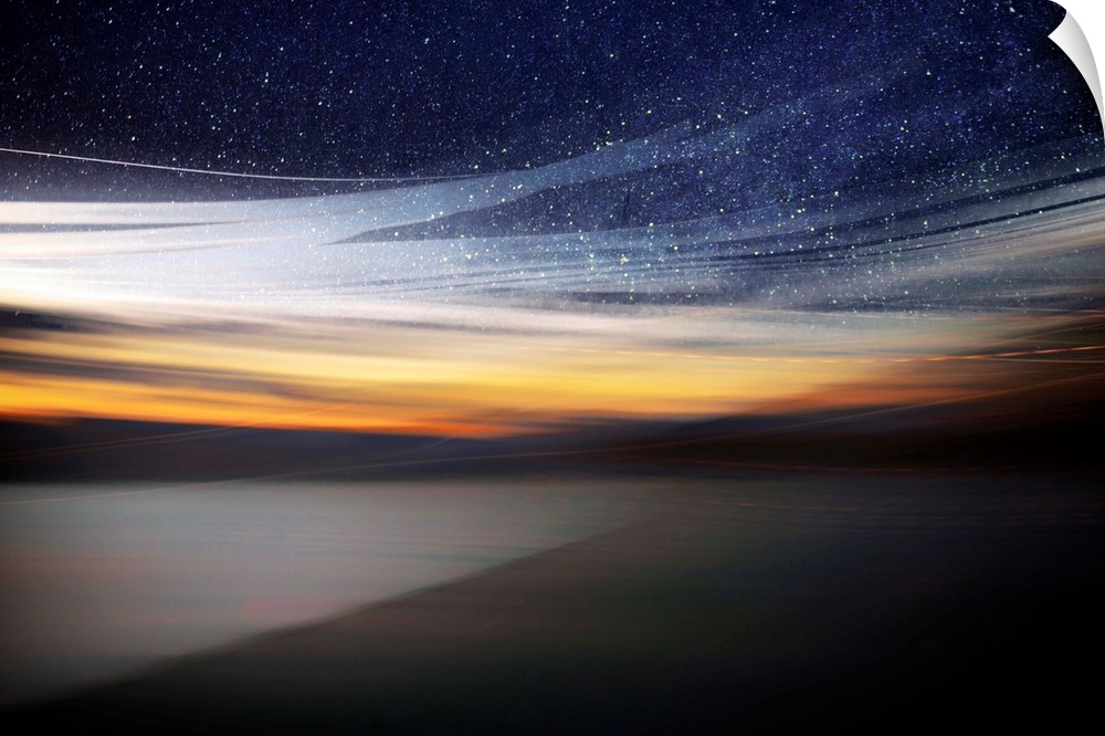 Fine art photo of a starry night sky over the light of the setting sun from the coast.