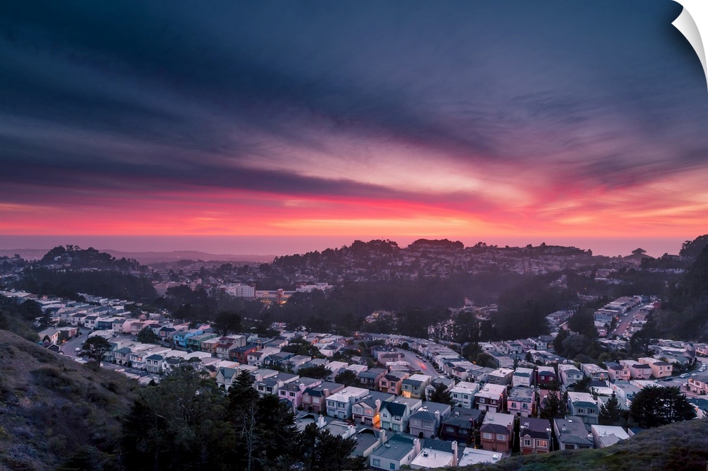 Dramatic pink and orange clouds over Twin Peaks in San Francisco during sunset.