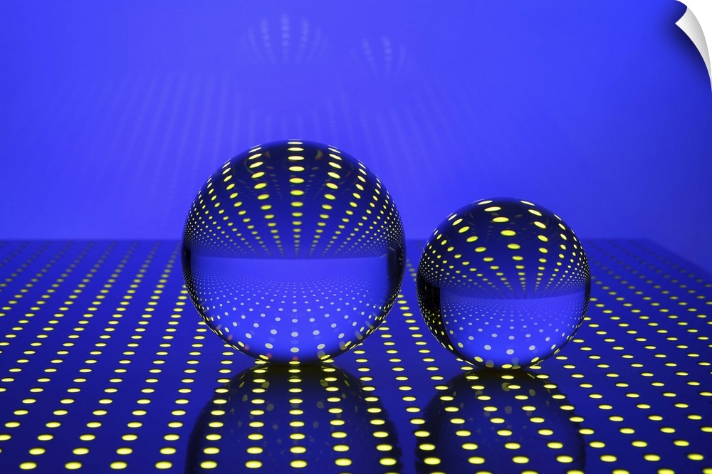 A photograph of glass orbs sitting on an illuminated polka dotted surface.