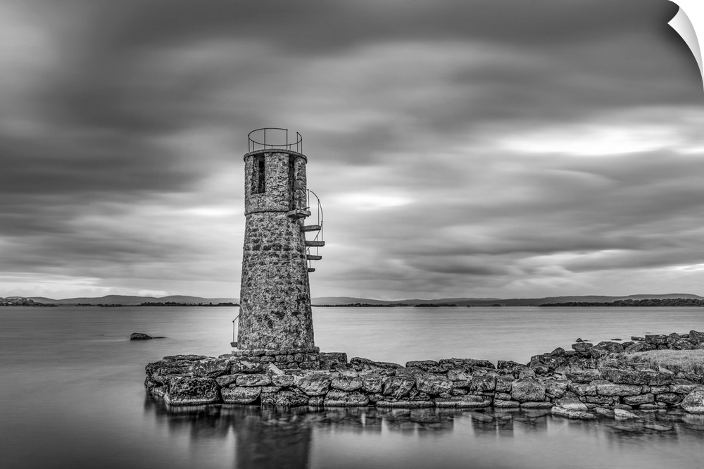 Black and white photo of an old lighthouse by a lake