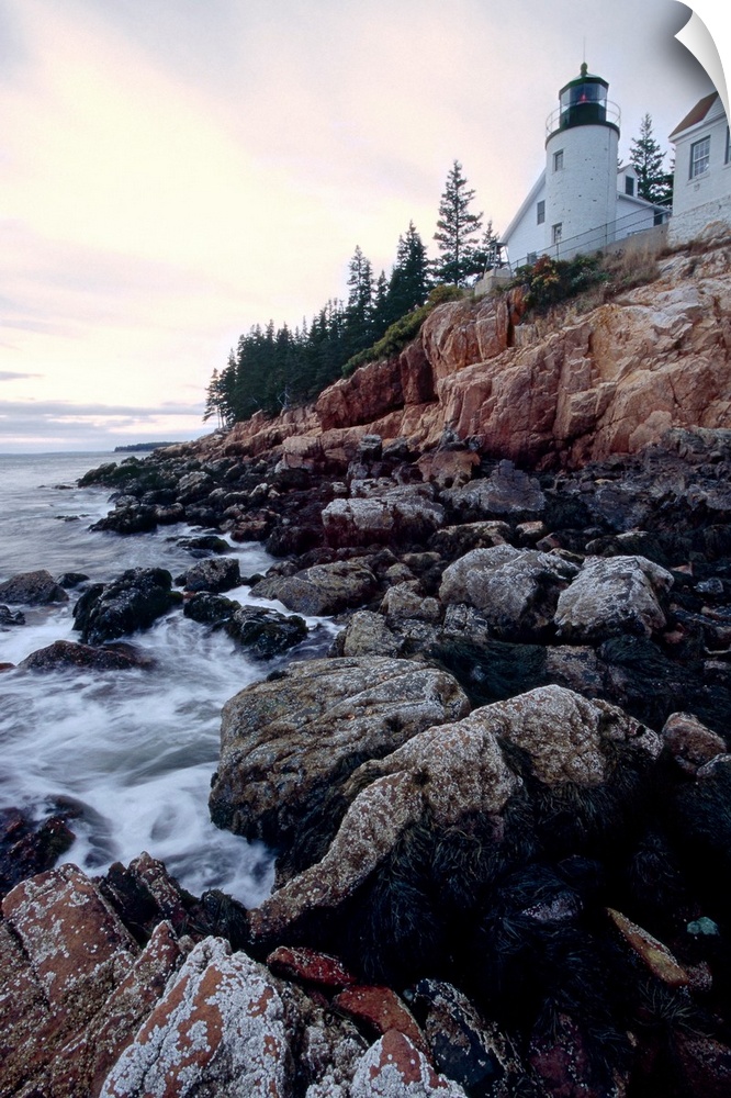 Low angle view of the bass harbor head lighthouse that sits atop a rocky cliff.