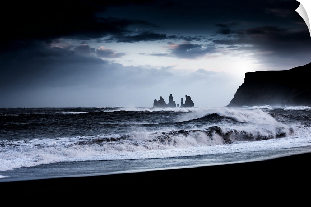 A photograph of a dark rugged coastline under a dark sky.