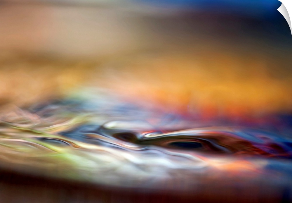 Abstract photograph of smooth liquid undulations reflecting various evening hues with a shallow depth-of-field.