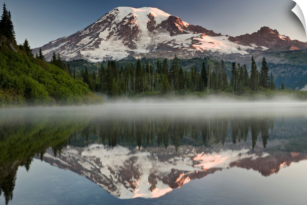 Big photograph shows the great size of snow-covered Mount Rainier in the background reflecting over one of the many lakes ...