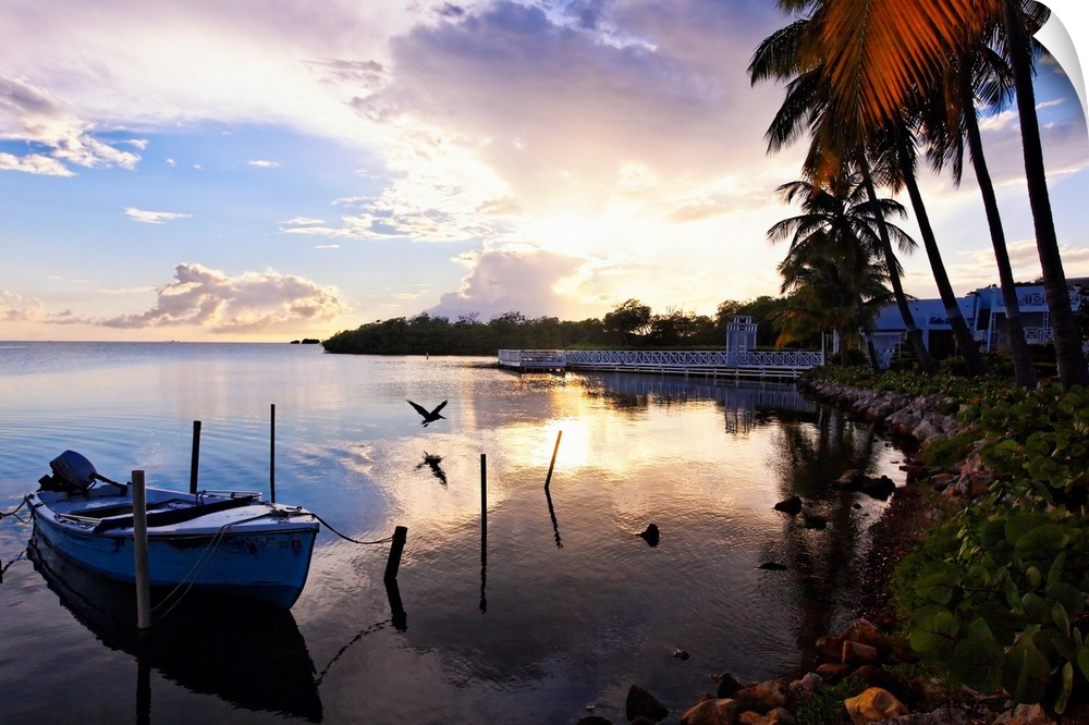 Large landscape photograph of the sun setting over the coast near a fishing village in La Parguera, Puerto Rico.  Palm tre...