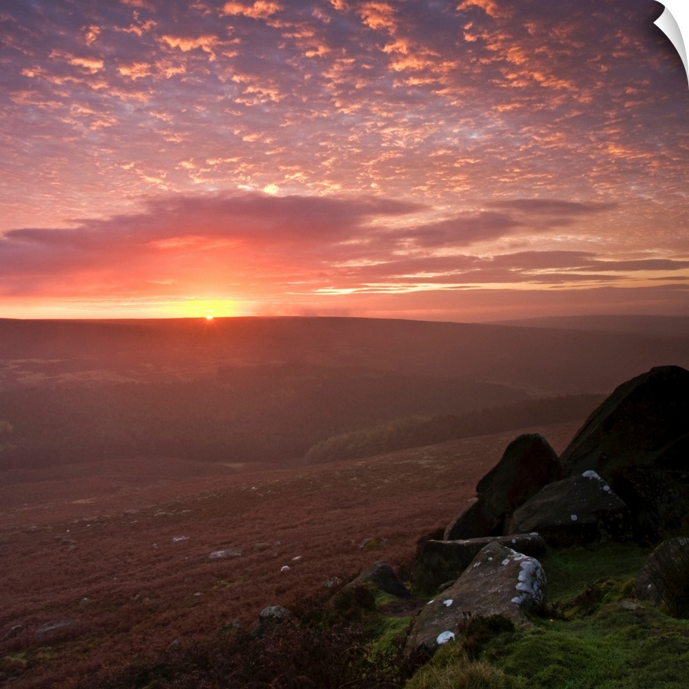 An optimistic golden yellow sunrise in the English Peak District National Park with fluffy clouds.