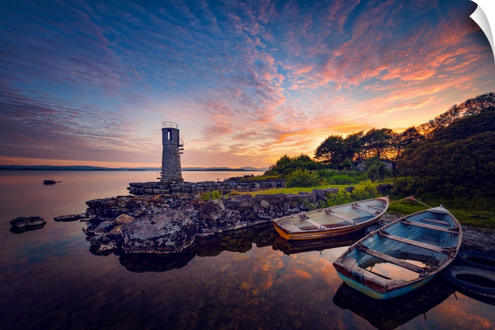 Sunset in Ireland with rowing boats in the foreground around a lighthouse