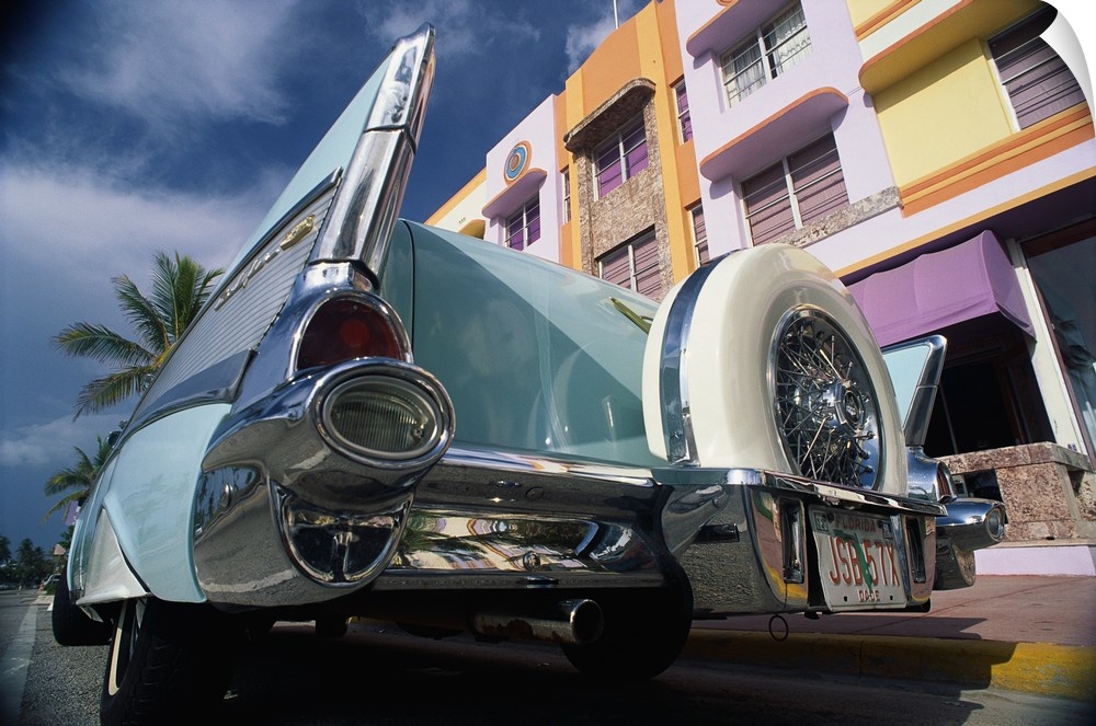 Up-close photograph of classic car from behind on street lined with colorful buildings.