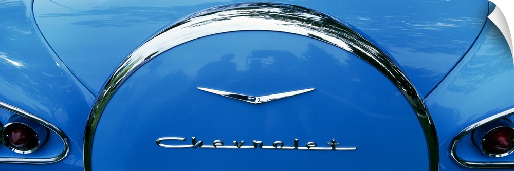 Oversized, landscape photograph of the back end of a shiny blue 1958 Chevrolet Bel-Air, including part of the trunk and ta...
