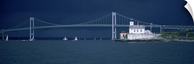 A storm approaches sailboats racing past Rose Island lighthouse and the Newport Bridge in Narragansett Bay, Newport, Rhode Island USA