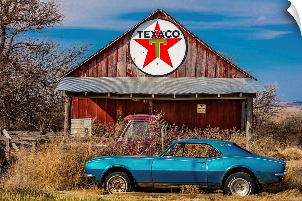 Abandoned blue camaro chevrolet in front of deserted texaco station, remote part of nebraska.