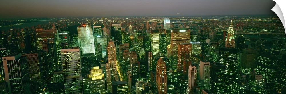 High angle view looking down at New York City and all the tall buildings glowing windows in the early night sky.
