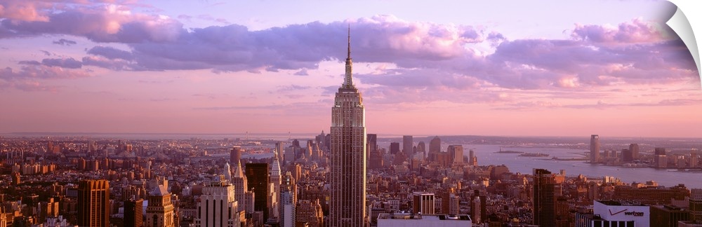 Aerial panoramic picture of New York City and the top of the Empire State Building in the pink glow of the sunset.