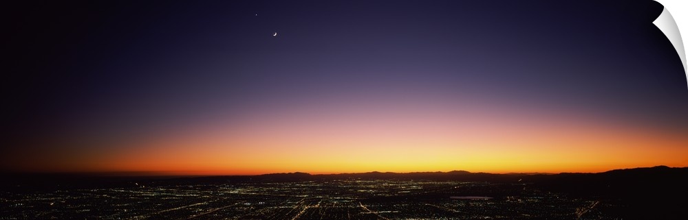 An aerial photograph taken of Los Angeles at night with the sun just setting below the horizon.