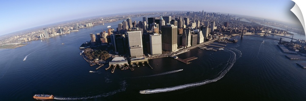 The Manhattan skyline is photographed from an aerial view showing the water that is surrounding it with boats driving arou...