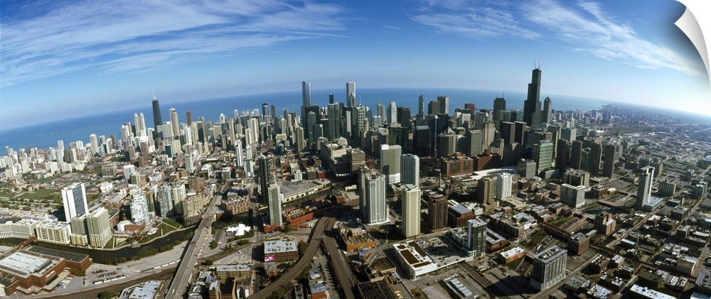 The city of Chicago is photographed from up high showing almost all of the skyscrapers and a large body of water behind it.