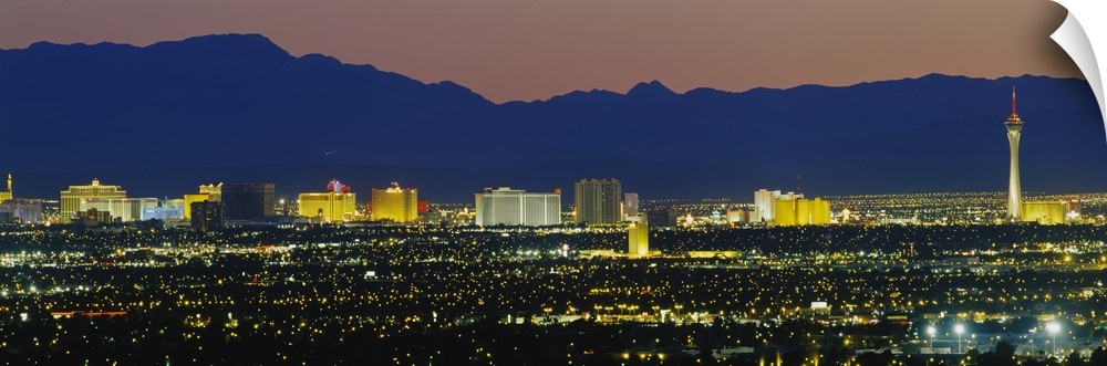 Panorama of Las Vegas skyline with the Rocky Mountains in the background at night.