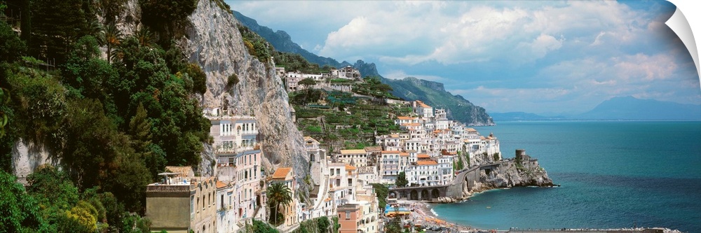 Wide angle photograph taken of buildings that sit in the mountains and line the ocean coast in Italy.
