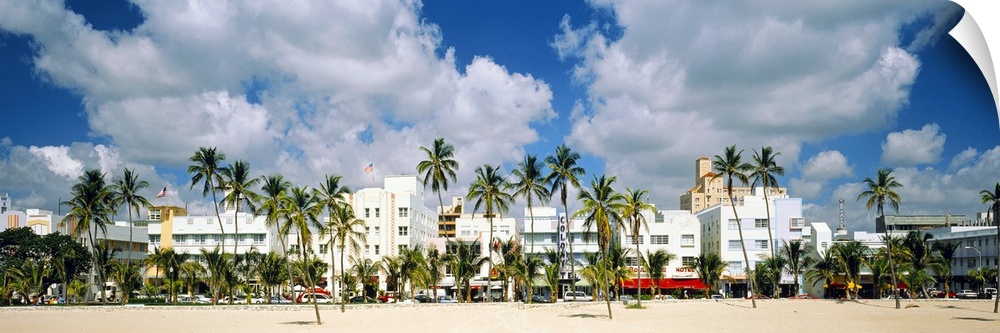 Panoramic photograph of beachfront lined with historic motels and palm trees under a cloudy sky.
