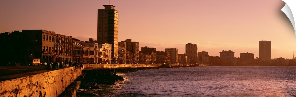 This wide angle picture is taken of buildings lining a body of water in Havana Cuba during sun down.