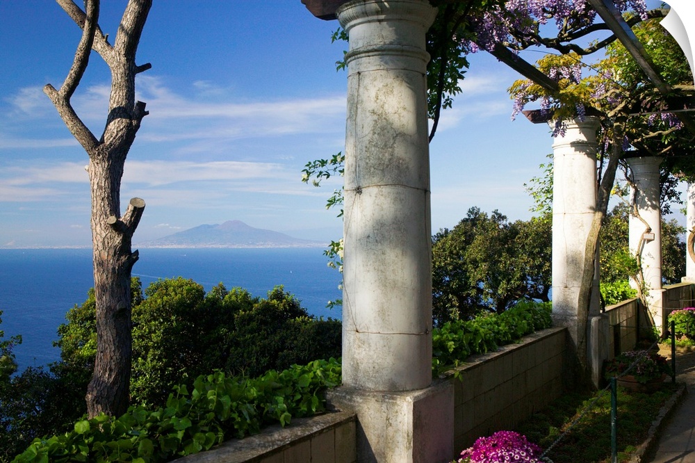 Large photograph taken from a European terrace filled with columns and bushes as it overlooks the Tyrrhenian Sea containin...