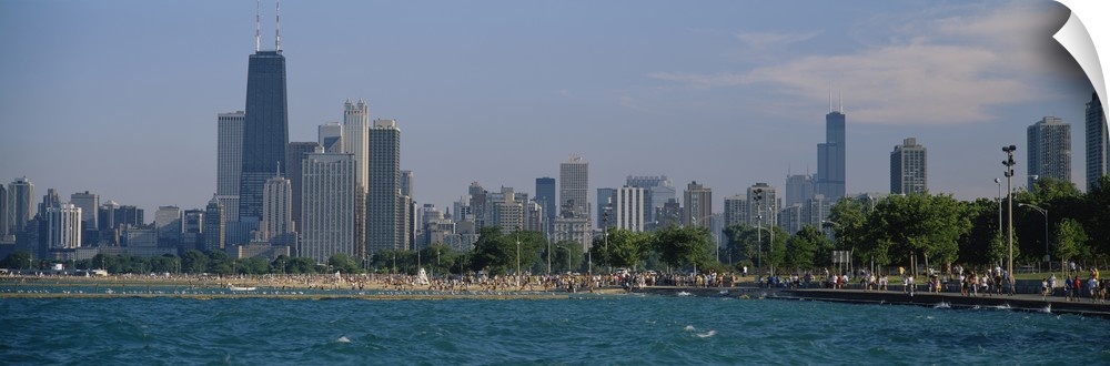 Oversized, landscape photograph of the Chicago skyline, a crowded beach at the waters edge in the foreground.