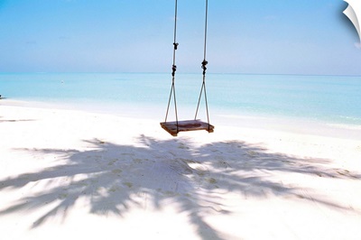 Beach swing and shadow of palm tree on sand
