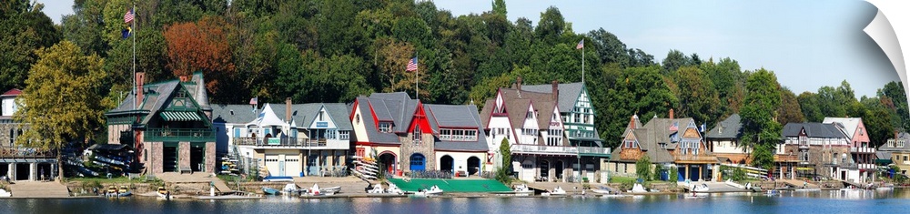 A panoramic photograph taken at midday in late summer of the boat houses that line the river.