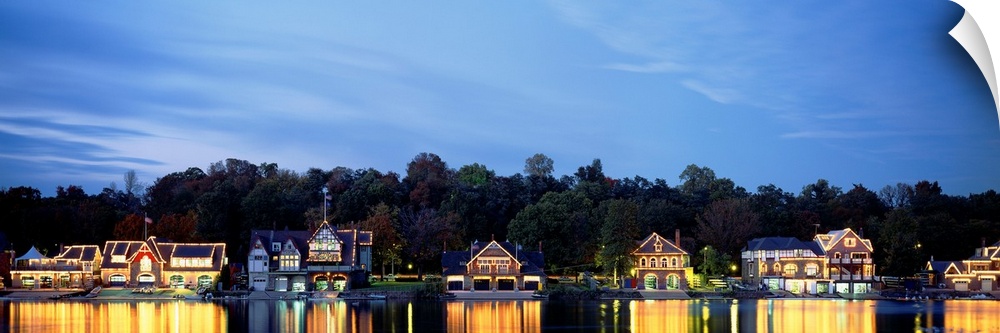 Panoramic photograph taken of Boathouse Row in Philadelphia at night with a backdrop full of trees.  The bright lights of ...