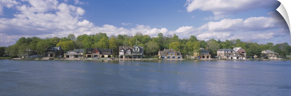 Panoramic photo of boathouses lining a waterfront.