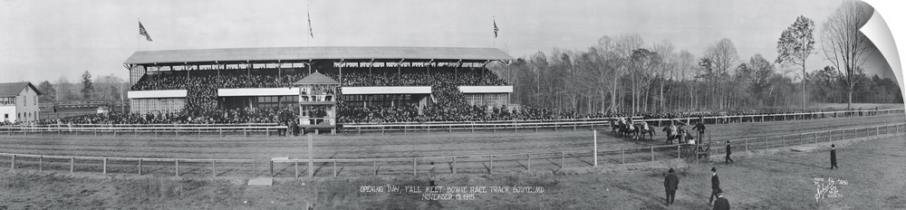 Panoramic vintage photograph of race track with people filled stands on the side.