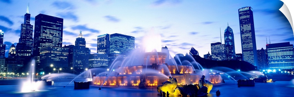A panoramic photograph of city skyline in the distance framing the fountain in the evening light.