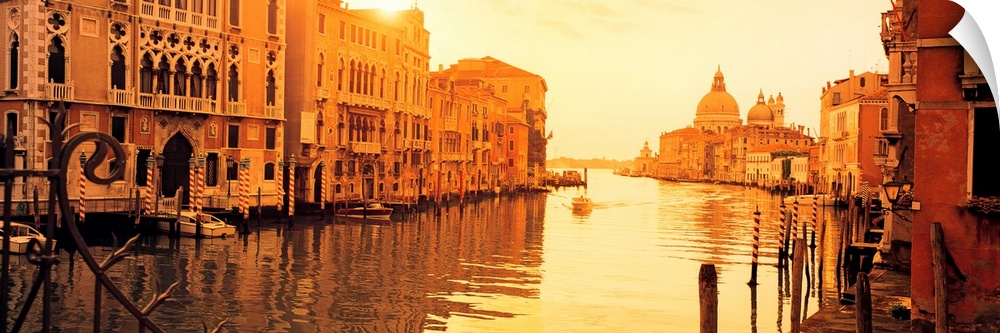 This panoramic photograph captures a still moment in the canals at sunset and this historic city as single gondola approac...