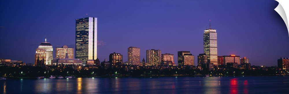 Large panoramic photograph of skyscrapers and other buildings lit up lining the Charles River in Boston, Massachusettes at...