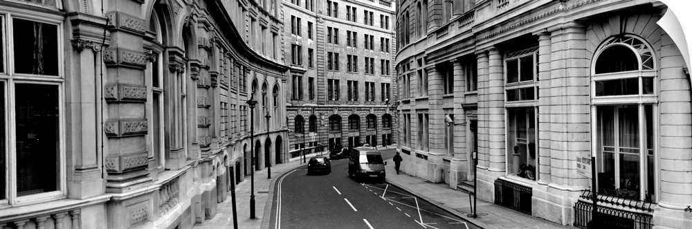 A narrow curved road lined with light stone covered buildings in downtown London.