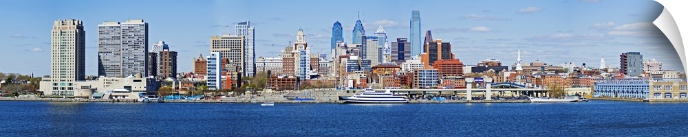 A panoramic photograph taken of the Philadelphia skyline during the day from just across the Delaware River.