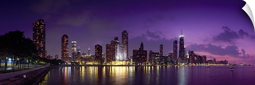 Long canvas photo of a lit up cityscape at sunset by a waterfront.