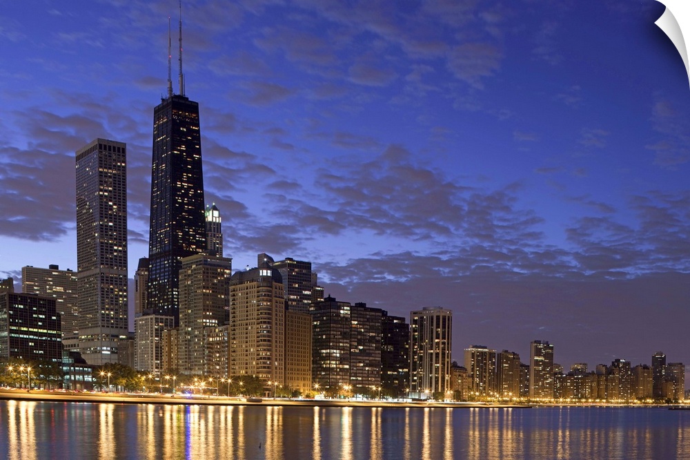 Large photo on canvas of the Chicago cityscape lit up at night reflecting into the nearby waterfront.