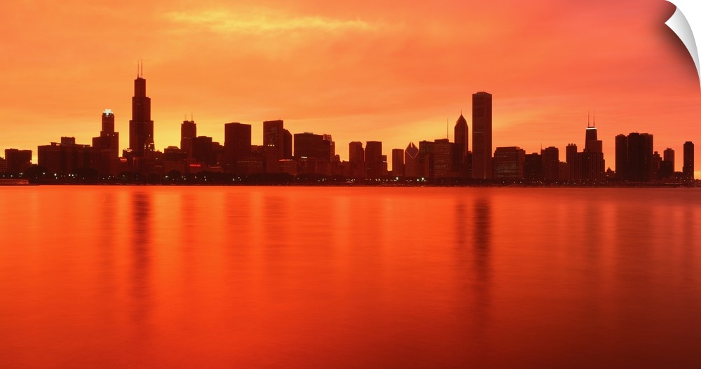 Large panoramic photograph of the Chicago, Illinois (IL) waterfront at dusk with the sun's rays reflecting off Lake Michigan.