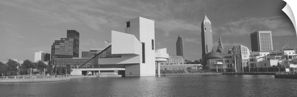 A black and white panoramic photograph taken of buildings in Cleveland sitting on water with the rock and roll hall of fam...