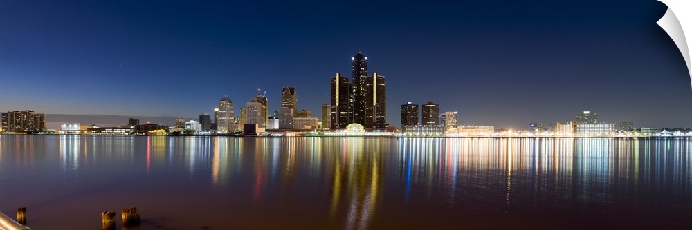 Panoramic photograph of skyline and waterfront at night.  The building lights create colorful reflections in the water.