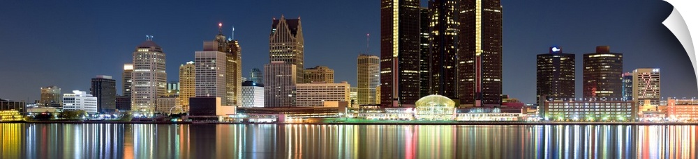 Panoramic photograph of skyline after sunset with city lights reflected in waterfront.