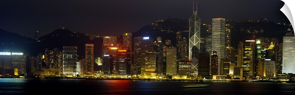 Panoramic photograph of the Hong Kong skyline, lit up at night, reflecting in the water, in China.