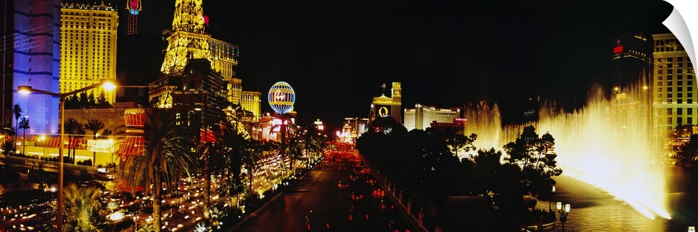 Panoramic photograph displays the brightly lit strip of Las Vegas, Nevada filled with hotels, casinos and a fountain in th...
