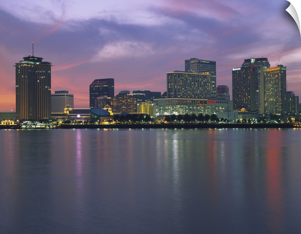Panoramic photograph of skyline at waterfront.  The building lights are reflected in the water below.
