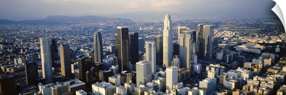 Wide angle, aerial photograph on a big canvas of the city of Los Angeles beneath a slightly hazy sky.