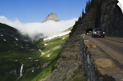 Cars on Going to the Sun Road through mountainside tunnel, low clouds in valley, Glacier National Park, Montana
