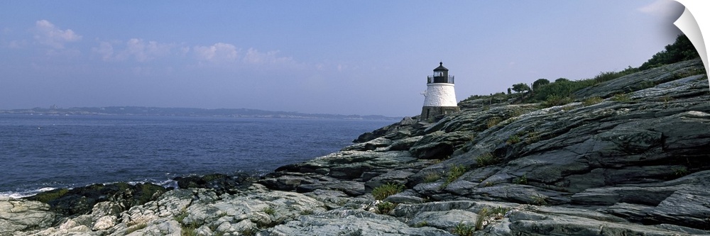 A small lighthouse sits on the edge of rocky terrain and overlooks the Atlantic ocean.